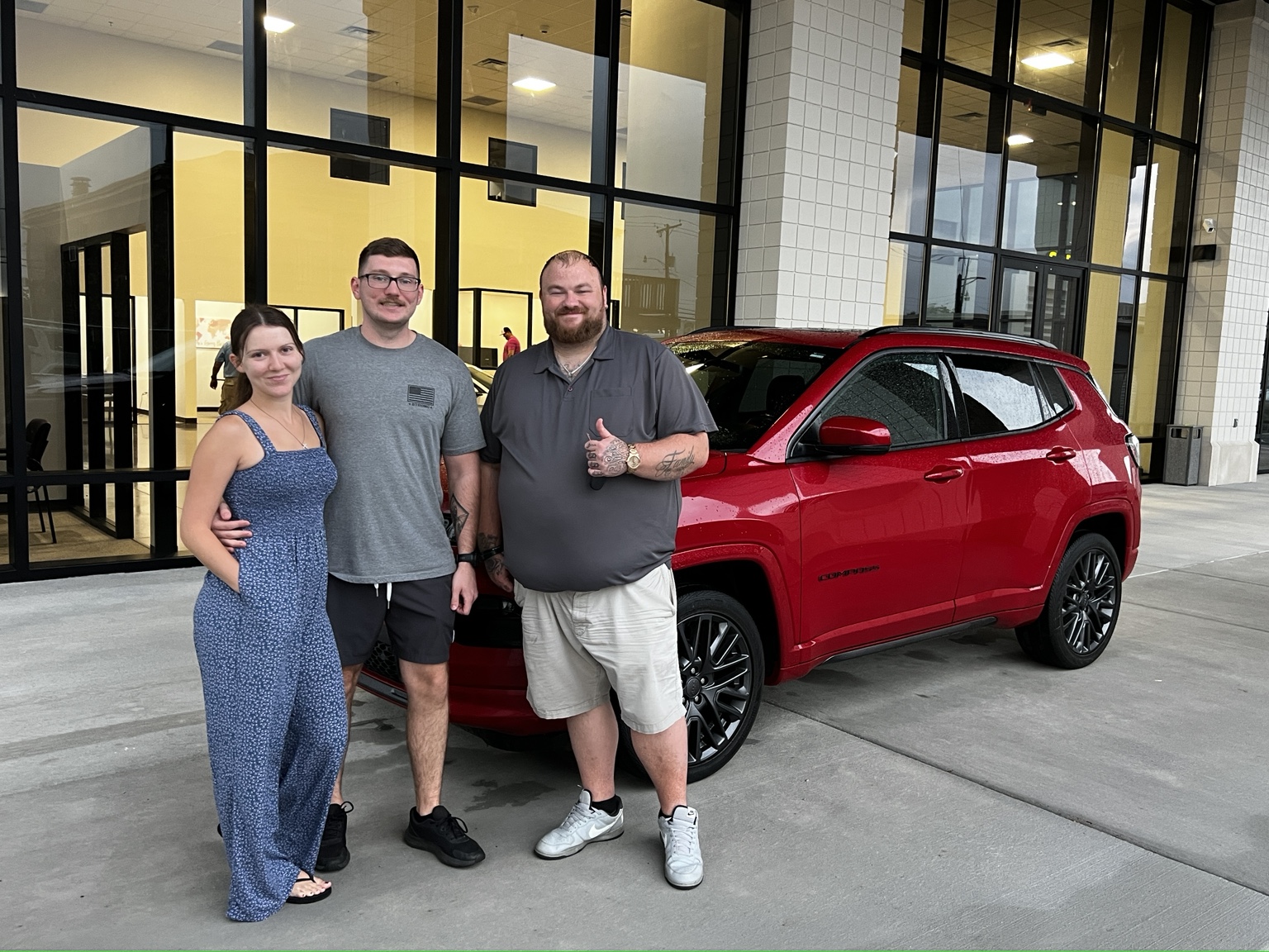 Darrell with customers and a red Jeep Compass