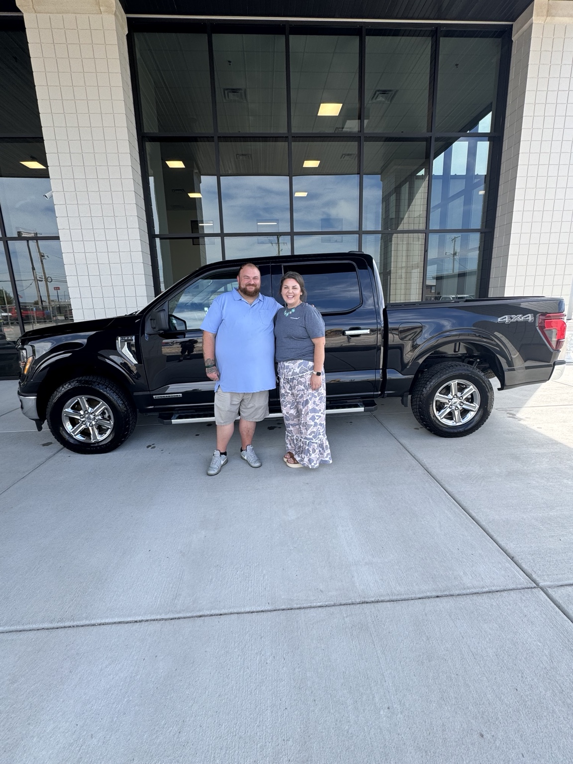 Happy customers with Darrell and a black Ford F-150