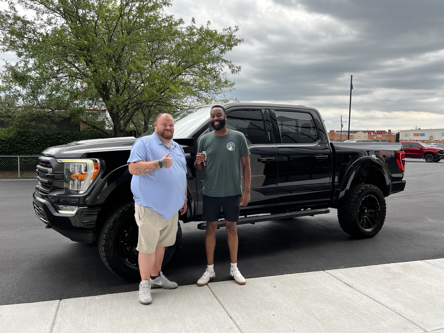 Darrell with a customer and a lifted black Ford F-150
