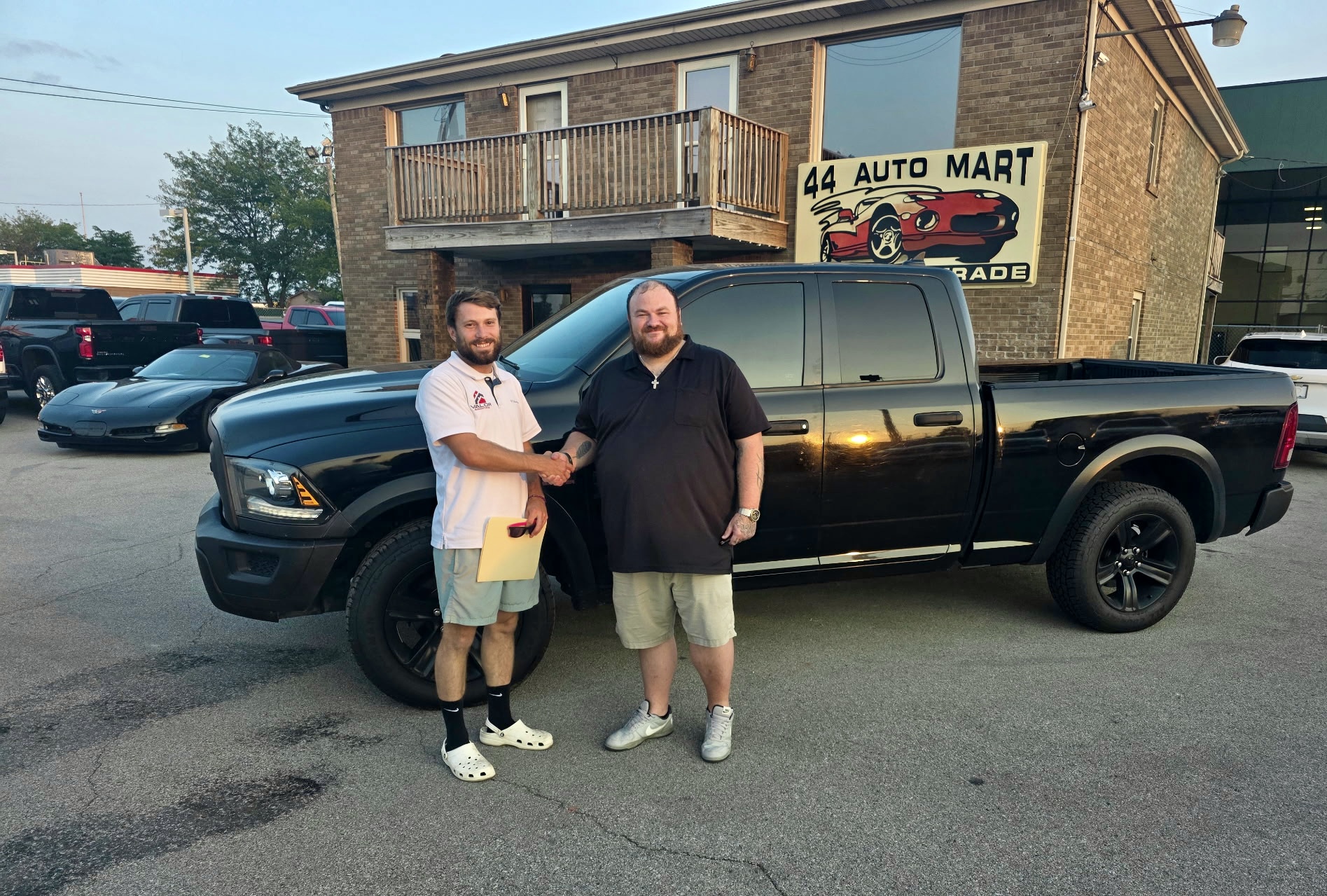 Darrell shaking hands with a customer beside a black Ram truck